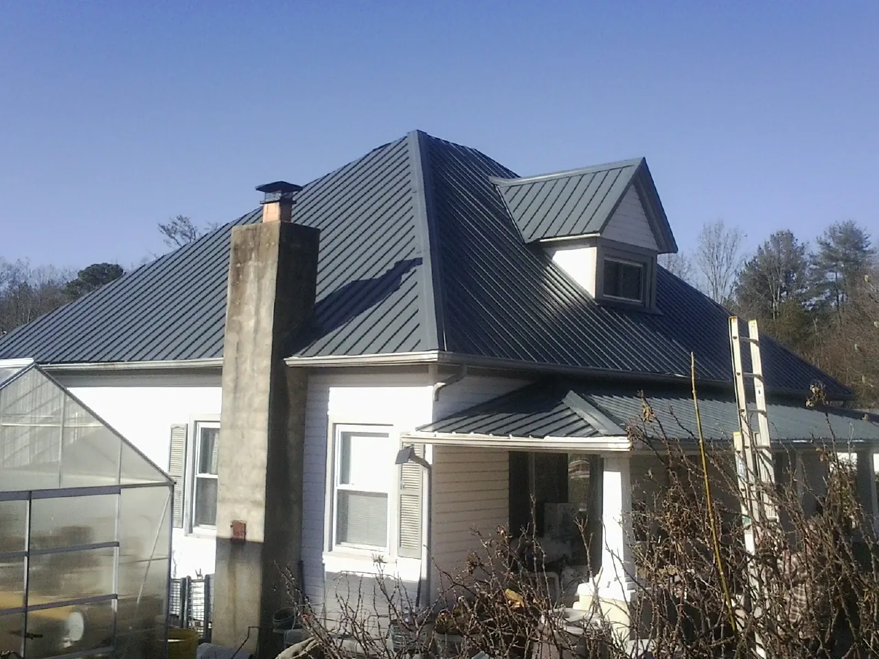 Dark blue standing seam metal roof on a white farmhouse with dormer — Slate & Tile Roof Repair by Roofing Brothers in Vaughan