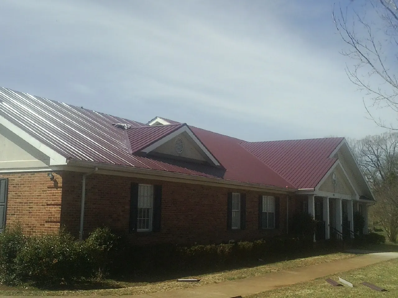 Red metal roof with gabled entries on a long brick building, from a Hail Damage Roof Repair job in Vaughan