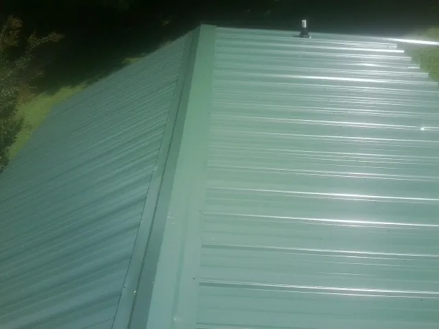 New green metal panels meeting at the ridge of a roof — Flat Roof Repair work by our crew in Vaughan
