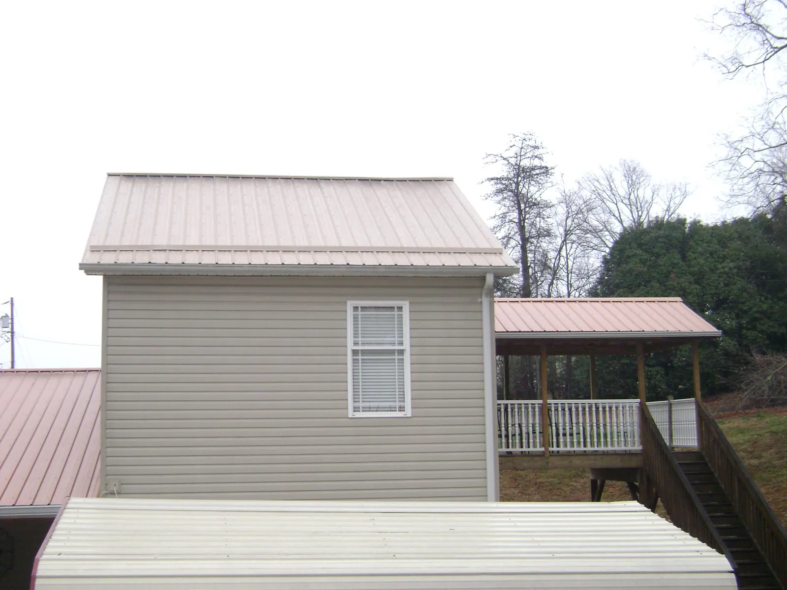 Tan metal roofs on a two story addition and attached porch, from a Roof Replacement job in Vaughan